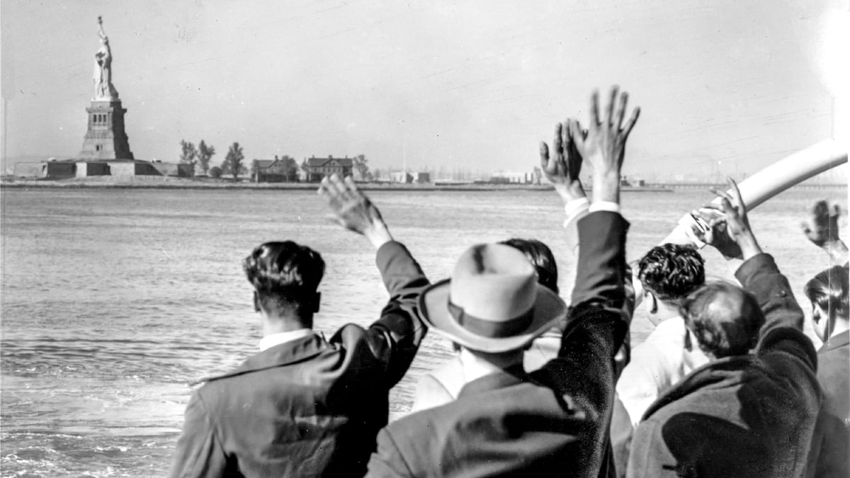 Historic photo of Italian migrants arriving in New York and waving at the Statue of Liberty. A poignant image contrasting with today's trend of descendants relocating to Italy with assistance from Why Wait Italy.