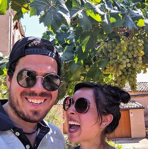 Smiling expat couple enjoying the Italian lifestyle under grape vines.