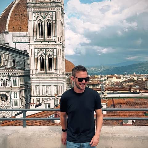 Smiling client of Why Wait Italy on a rooftop terrace in front of the Florence Duomo.