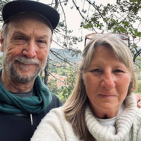 Smiling couple, previous clients of Why Wait Italy, taking a selfie above an Italian hillside town.